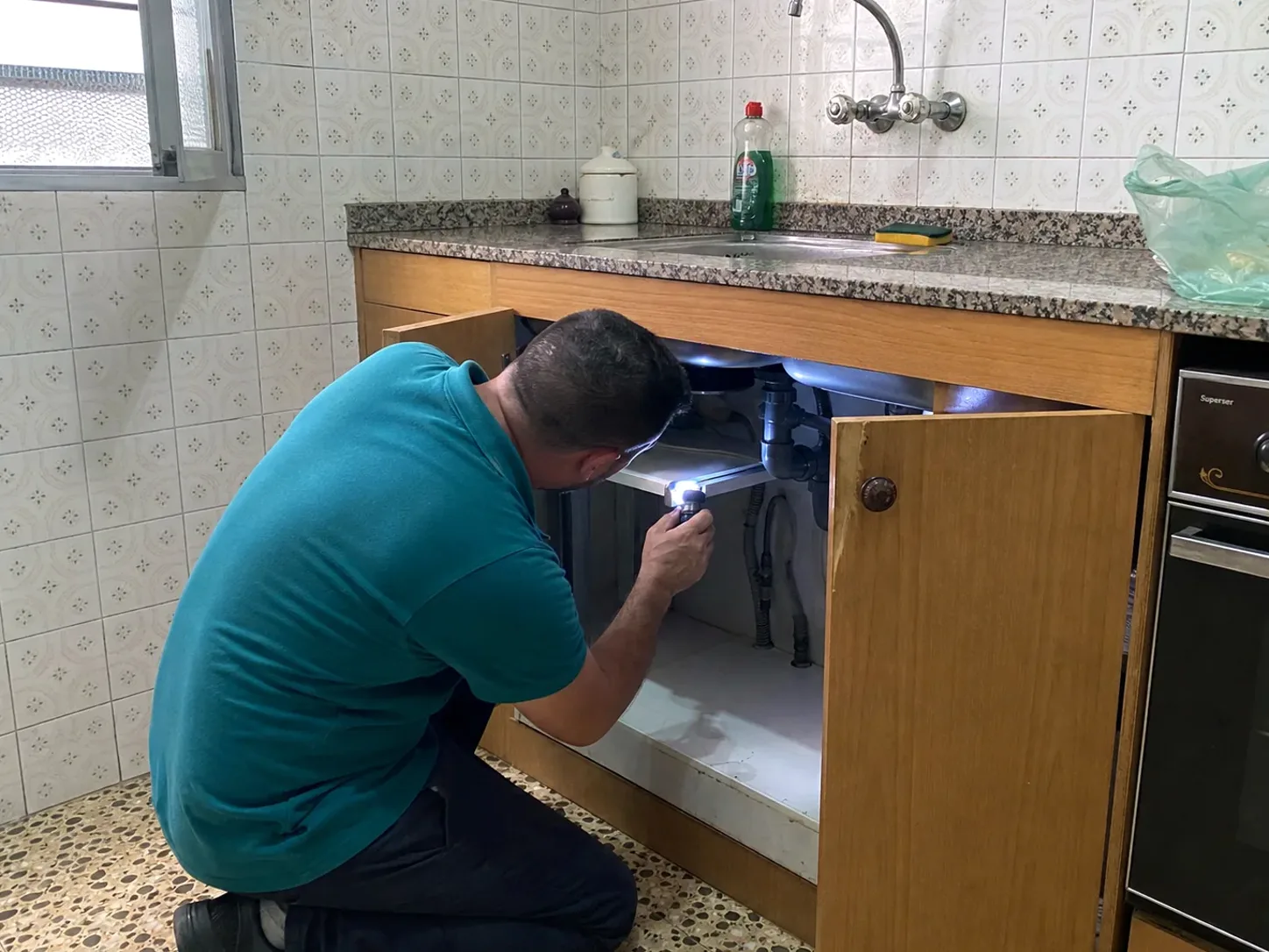 Técnico de RipolPlagas inspeccionando una cocina con linterna
